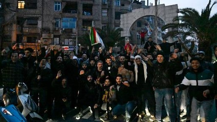Local residents cheer as the gather on a street in the Damascus suburb of Jaramana on December 8, 2024. Syrian rebels said on December 8 that President Bashar al-Assad had fled the country, calling on citizens abroad to return to a free Syria and saying that Damascus was free of the tyrant. (Photo by LOUAI BESHARA / AFP)