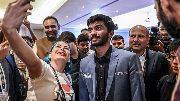 A fan takes a selfie with India's grandmaster Gukesh Dommaraju (C) after his win against China's chess grandmaster Ding Liren in game 14 of the 2024 FIDE World Championship in Singapore on December 12, 2024. The 18-year-old became 