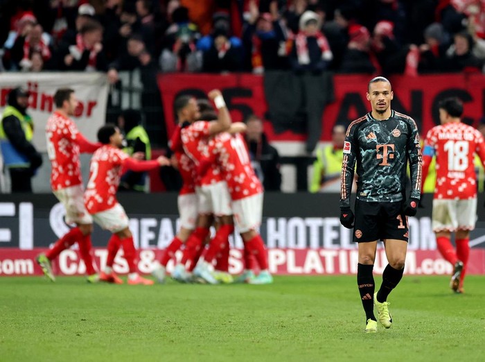 MAINZ, GERMANY - DECEMBER 14: Leroy Sane of Bayern Munich looks dejected as Lee Jae-Song of 1.FSV Mainz 05 (obscured) celebrates scoring his team's second goal with teammates during the Bundesliga match between 1. FSV Mainz 05 and FC Bayern München at MEWA Arena on December 14, 2024 in Mainz, Germany. (Photo by Alex Grimm/Getty Images)