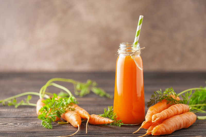Fresh  carrot juice in glass bottle on a  wooden table