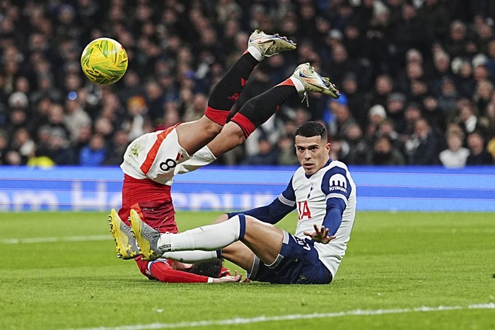 Tottenham's Pedro Porro, right, challenges for the ball with Manchester United's Bruno Fernandes during the English League Cup quarter-final soccer match between Tottenham and Manchester United, at the Tottenham Hotspur Stadium in London, Thursday, Dec. 19, 2024. (AP Photo/Dave Shopland )