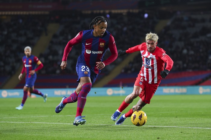 BARCELONA, SPAIN - DECEMBER 03: Jules Kounde of FC Barcelona challenges for the ball against Rodrigo de Paul of Atletico de Madrid during the LaLiga EA Sports match between FC Barcelona and Atletico Madrid at Estadi Olimpic Lluis Companys on December 03, 2023 in Barcelona, Spain. (Photo by Eric Alonso/Getty Images)