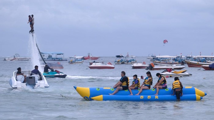 Wisatawan bermain wahana banana vessel di Pantai Tanjung Benoa, Kuta Selatan, Badung, Bali, Rabu (25/12/2024). Kunjungan wisata di pantai yang terkenal dengan wahana h2o athletics tersebut didominasi wisatawan nusantara pada liburan Natal. ANTARA FOTO/Nyoman Hendra Wibowo/wpa.