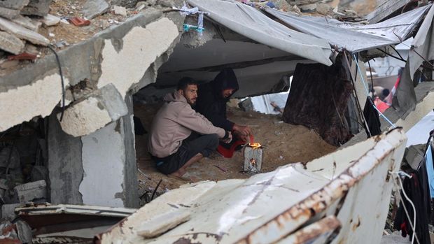 Seorang pengungsi Palestina membersihkan air dari tendanya di kamp darurat saat terjadi badai di Kota Gaza pada 31 Desember 2024, di tengah perang yang sedang berlangsung antara Israel dan kelompok militan Hamas. (Foto oleh Omar AL-QATTAA / AFP)