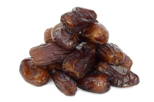 Pile of Deglet Nour dates grown in Tunisia, on a white background. Deglet Nour dates have a characteristic translucent blond colour and soft caramel-like taste which distinguishes them from all other dates.