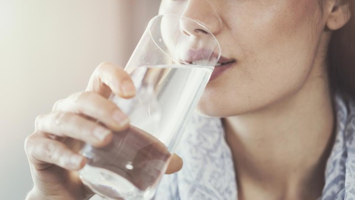 Ilustrasi perempuan minum air putih Young woman drinking pure glass of water