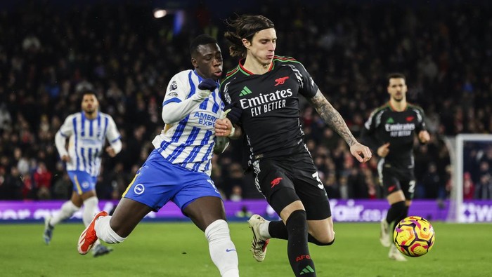 CORRECTS NAME BRIGHTON PLAYER - Brightons Yankuba Minteh, left, duels for the ball with Arsenals Riccardo Calafiori during the English Premier League soccer match between Brighton and Hove Albion FC and Arsenal at the Amex stadium in Brighton, Saturday, Jan. 4, 2025. (AP Photo/Ian Walton)