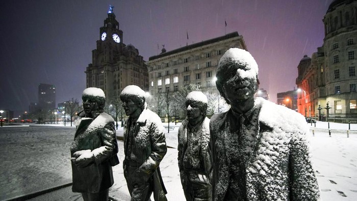 Snow falls on the Beatles Statue at Pier Head, Liverpool. Much of Britain is facing another day of cold temperatures and travel disruption after overnight lows dropped below freezing for the bulk of the country. A 
