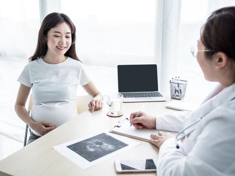 Pregnant woman with doctor looking at ultra sound photo in hospital