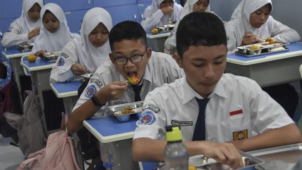 Siswa menyantap makanan bergizi gratis di SMP Negeri 2 Tasikmalaya, Kota Tasikmalaya, Jawa Barat, Senin (6/1/2025). Satuan Pelayanan Pemenuhan Gizi (SPPG) Tasikmalaya membagikan 2.999 paket makanan bergizi gratis kepada siswa di tujuh sekolah tingkat PAUD hingga SMA di Kota Tasikmalaya dengan menu makan berisi nasi, ayam goreng, tempe, tumis bucis dan wortel serta jeruk. ANTARA FOTO/Adeng Bustomi