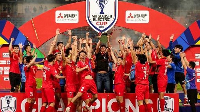 Vietnams South Korean head coach Kim Sang-sik (C) and Vietnams players celebrate with the trophy after winning the 2024 ASEAN Electric Cup final second leg football match between Thailand and Vietnam at the Rajamangala National Stadium in Bangkok on January 5, 2025. (Photo by Chanakarn LAOSARAKHAM / AFP)