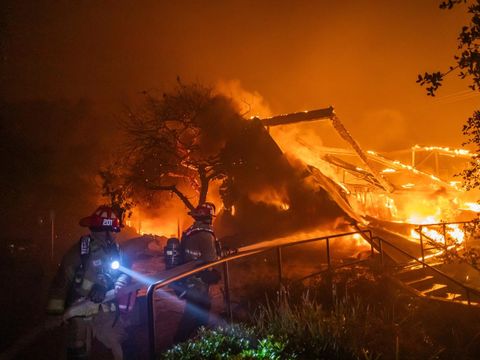  Firefighters fight the flames from the Palisades Fire burning the Theatre Palisades during a powerful windstorm on January 8, 2025 in the Pacific Palisades neighborhood of Los Angeles, California. The fast-moving wildfire is threatening homes in the coastal neighborhood amid intense Santa Ana Winds and dry conditions in Southern California.   Apu Gomes/Getty Images/AFP (Photo by Apu Gomes / GETTY IMAGES NORTH AMERICA / Getty Images via AFP)