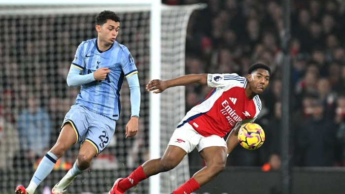 LONDON, ENGLAND - JANUARY 15: Myles Lewis-Skelly of Arsenal runs with the ball whilst under pressure from Brennan Johnson of Tottenham Hotspur during the Premier League match between Arsenal FC and Tottenham Hotspur FC at Emirates Stadium on January 15, 2025 in London, England. (Photo by Stuart MacFarlane/Arsenal FC via Getty Images)