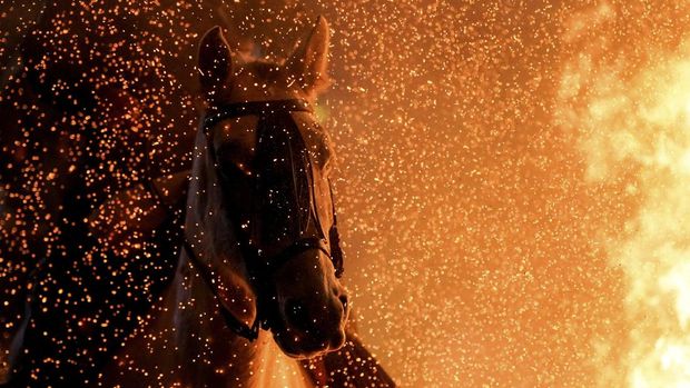 A person rides a horse through flames during the annual 