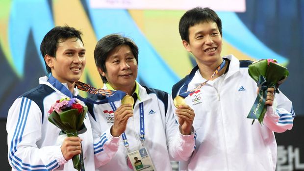 Ahsan/Hendra Galfot Testimonial Day Gold medalists Indonesia's Mohammad Ahsan (L) and Hendra Setiawan (R) pose with their coach Herry Iman Pierngadi (C) on the podium after the men's doubles badminton final at Gyeyang gymnasium during the 2014 Asian Games in Incheon on September 28, 2014. AFP PHOTO/ROSLAN RAHMAN (Photo by ROSLAN RAHMAN / AFP)