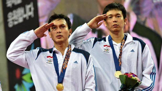 Gold medalists Indonesia's Mohammad Ahsan (L) and Hendra Setiawan (R) salute on the podium after the men's doubles badminton final at Gyeyang gymnasium during the 2014 Asian Games in Incheon on September 28, 2014.  AFP PHOTO/ROSLAN RAHMAN (Photo by ROSLAN RAHMAN / AFP)