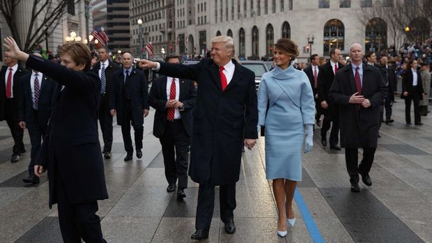 President Donald Trump waves as he walks with first lady Melania Trump during the inauguration parade in Washington, DC, on January 20, 2017 following swearing-in ceremonies on Capitol Hill earlier today. (Photo by Evan Vucci / POOL / AFP)