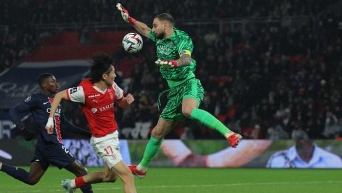 Paris Saint-Germains Italian goalkeeper #01 Gianluigi Donnarumma (C) leaps into the air to save a shot from Reims Japanese forward #17 Keito Nakamura (2L) during the French L1 football match between Paris Saint-Germain (PSG) and Stade de Reims at the Parc des Princes Stadium in Paris on January 25, 2025. (Photo by Thomas SAMSON / AFP)