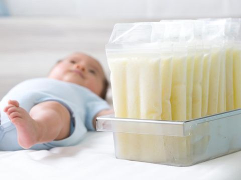 Breast milk frozen in storage bag and baby lying on background
