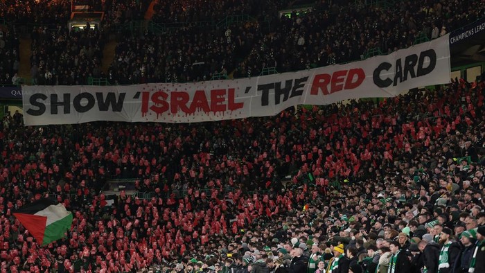 Soccer Football - Champions League - Knockout Phase Playoff - First Leg - Celtic v Bayern Munich - Celtic Park, Glasgow, Scotland, Britain - February 12, 2025 A Palestine flag is seen as Celtic fans display a banner stating show Israel the red card amid a ceasefire between Israel and Hamas Action Images via Reuters/Lee Smith