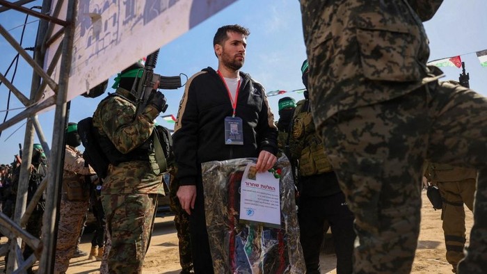 Militan Hamas menemani sandera Israel-Amerika, Sagui Dekel-Chen, salah satu dari tiga sandera yang dibebaskan di Gaza pada Sabtu (15/2) waktu setempat Hamas militants escort Israeli-American hotsage Sagui Dekel-Chen on a stage before handing him over to a Red Cross team in Khan Yunis, southern Gaza Strip, on February 15, 2025, as part of the sixth hostage-prisoner exchange. (Photo by Bashar TALEB / AFP)