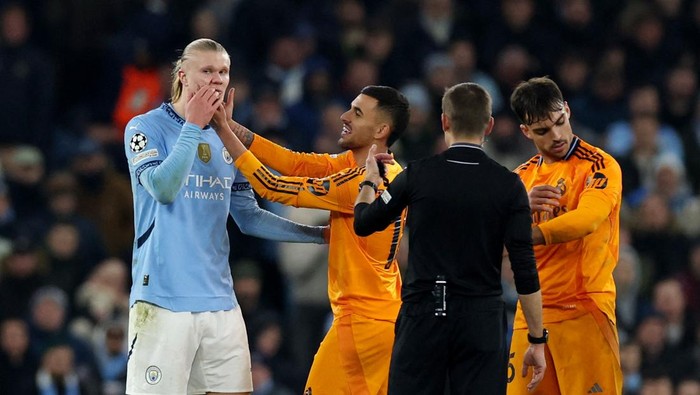 Soccer Football - Champions League - Knockout Phase Playoff - First Leg - Manchester City v Real Madrid - Etihad Stadium, Manchester, Britain - February 11, 2025  Manchester Citys Erling Haaland with Real Madrids Dani Ceballos, Real Madrids Raul Asencio and referee Clement Turpin REUTERS/Phil Noble