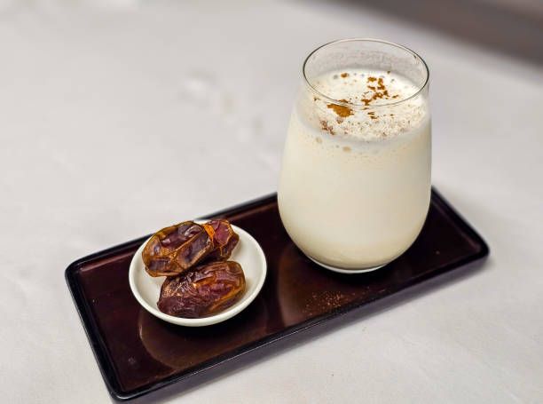 Dates and date smoothie with cinnamon powder on the top and serve with rectanguler tray.