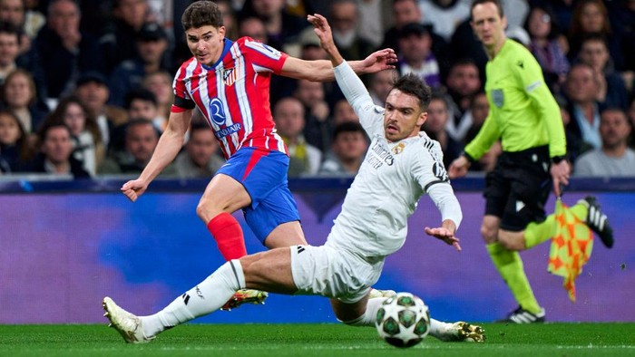 MADRID, SPAIN - MARCH 04: Julian Alvarez of Atletico de Madrid passes the ball past Raul Asencio of Real Madrid CF during the UEFA Champions League 2024/25 UEFA Champions League 2024/25 Round of 16 first leg match between Real Madrid C.F. and Atletico de Madrid at Santiago Bernabeu stadium on March 04, 2025 in Madrid, Spain. (Photo by Diego Souto/Getty Images)