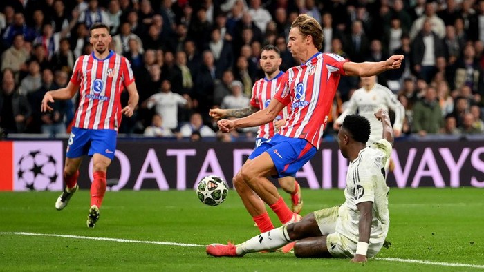 MADRID, SPAIN - MARCH 04: Vinicius Junior of Real Madrid shoots at goal whilst under pressure from Marcos Llorente of Atletico de Madrid during the UEFA Champions League 2024/25 Round of 16 first leg match between Real Madrid C.F. and Atletico de Madrid at Santiago Bernabeu Stadium on March 04, 2025 in Madrid, Spain. (Photo by Denis Doyle/Getty Images)