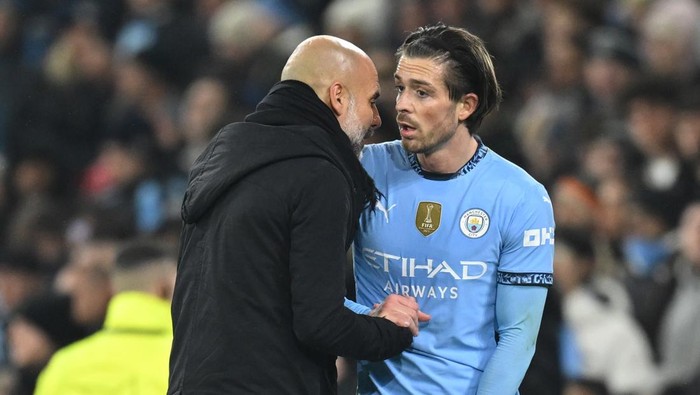 MANCHESTER, ENGLAND - FEBRUARY 11: Pep Guardiola, Manager of Manchester City, speaks to Jack Grealish of Manchester City as he leaves the pitch after picking up an injury during the UEFA Champions League 2024/25 League Knockout Play-off first leg match between Manchester City and Real Madrid C.F. at Manchester City Stadium on February 11, 2025 in Manchester, England. (Photo by Michael Regan/Getty Images)