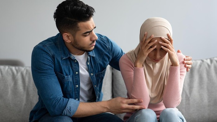 Ilustrasi suami istri Middle-eastern bearded man comforting his crying wife, young muslim couple having problems in relationships, visiting family therapist together. Frustrated lady in hijab feeling unhappy