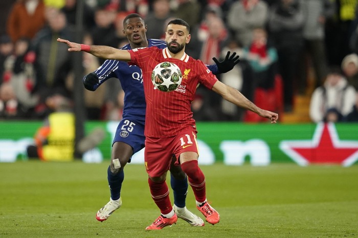 Liverpools Mohamed Salah shields the ball from PSGs Nuno Mendes during the Champions League round of 16 second leg soccer match between Liverpool and Paris Saint-Germain at Anfield in Liverpool, England, Tuesday, March 11, 2025. (AP Photo/Dave Thom