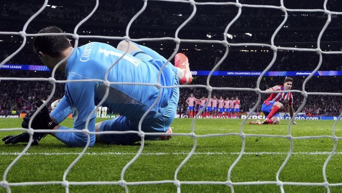 Atletico Madrids Julian Alvarez, right, stands up after falling to the ground when taking a penalty kick during a shootout at the end of the Champions League round of 16, second leg, soccer match between Atletico Madrid and Real Madrid at the Metropolitano stadium in Madrid, Spain, Wednesday, March 12, 2025. (AP Photo/Manu Fernandez)