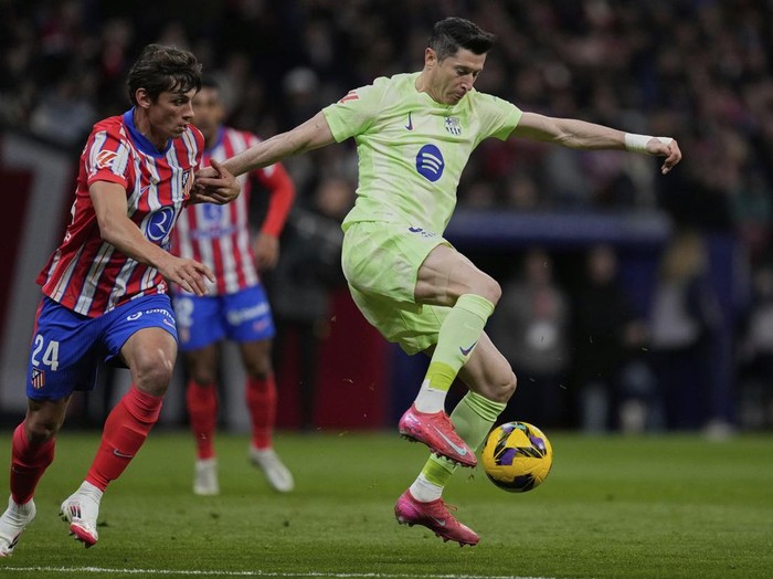 Barcelona's Robert Lewandowski, right, controls the ball challenged by Atletico Madrid's Robin Le Normand during a La Liga soccer match between Atletico Madrid and FC Barcelona at the Metropolitano stadium in Madrid, Sunday, March 16, 2025. (AP Photo/Bernat Armangue)