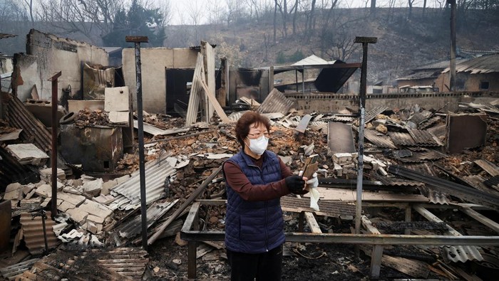 Kun Yeong-nam, 72, uses her mobile phone near her burnt house, where she lived for 52 years, after a wildfire devastated the area in Uiseong, South Korea March 27, 2025.REUTERS/Kim Hong-Ji
