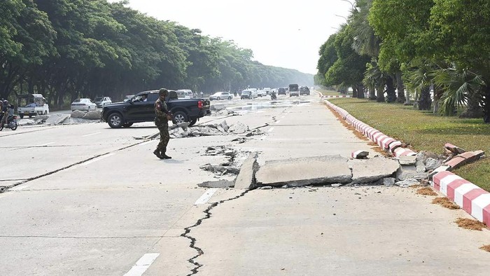Penampakan Jalan di Myanmar Hancur Akibat Gempa M 7,7 In this image provided by The Myanmar Military True News Information Team, a soldier provide security while vehicles make their ways near damaged road caused by an earthquake Friday, March 28, 2025, in Naypyitaw, Myanmar. (The Myanmar Military True News Information Team via AP) gempa
