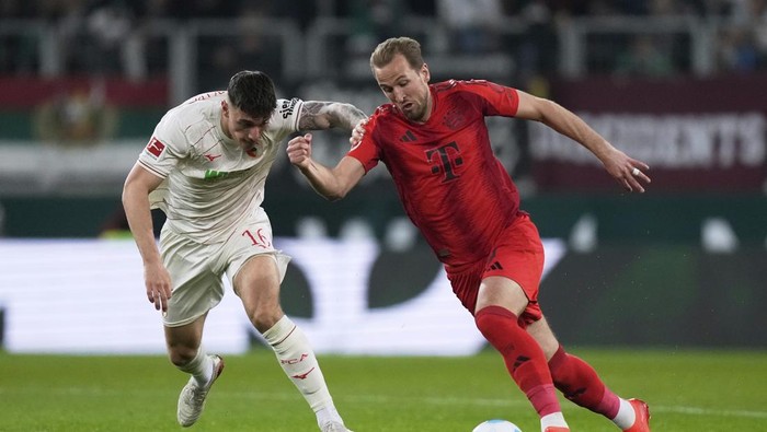 Bayern Munich, Harry Kane Augsburgs Cedric Zesiger, left, and Bayerns Harry Kane fight for the ball during the German Bundesliga soccer match between Augsburg and Bayern Munich in Augsburg, Friday, April 4, 2025. (AP Photo/Matthias Schrader)