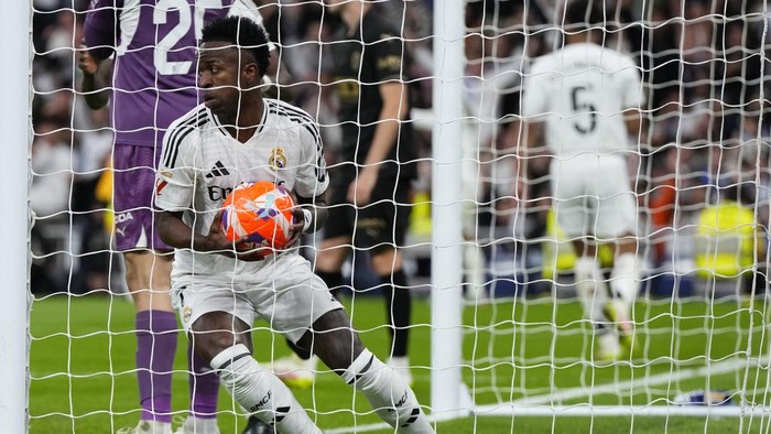 Real Madrid Real Madrids Vinicius Junior picks up the ball after scoring his sides first goal against Valencia during a Spanish La Liga soccer match between Real Madrid and Valencia at the Santiago Bernabeu stadium in Madrid, Spain, Saturday, April 5, 2025. (AP Photo/Manu Fernandez)