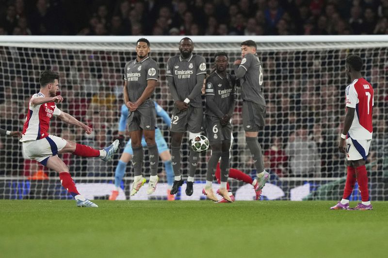 Arsenal's Declan Rice, left, scores his side's opening goal during the Champions League quarterfinal first leg soccer match between Arsenal and Real Madrid at the Emirates Stadium in London, Tuesday, April 8, 2025. (AP Photo/Frank Augstein)
