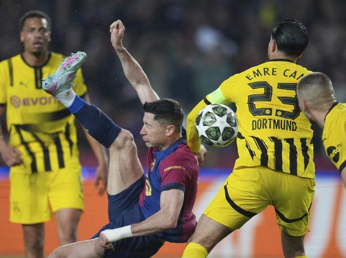 Barcelona's Robert Lewandowski, center, attempts a shot at goal in front of Dortmund's Emre Can during the Champions League quarterfinal first leg soccer match between Barcelona and Borussia Dortmund, at the Lluis Companys Olympic stadium in Barcelona, Spain, Wednesday, April 9, 2025. (AP Photo/Emilio Morenatti)
