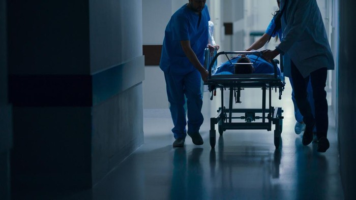 Emergency Department: Doctors, Nurses and Paramedics Push Gurney / Stretcher with Seriously Injured Patient towards the Operating Room.