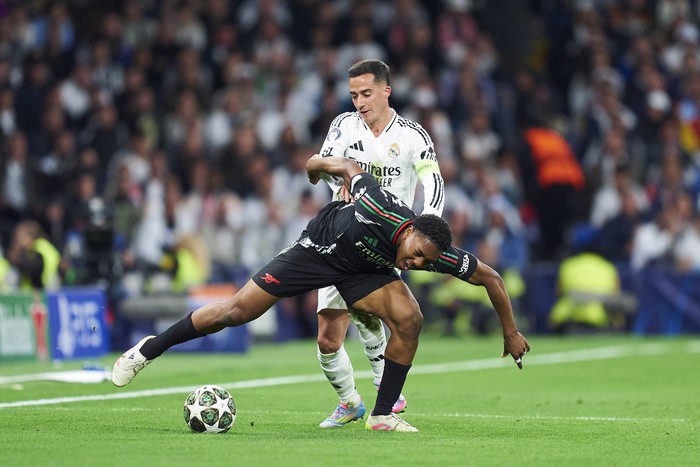 MADRID, SPAIN - APRIL 16: Lucas Vazquez (back) of Real Madrid competes for the ball with Myles Lewis-Skelly of Arsenal FC during the UEFA Champions League 2024/25 Quarter Final Second Leg match between Real Madrid C.F. and Arsenal FC at Estadio Santiago Bernabeu on April 16, 2025 in Madrid, Spain. (Photo by Mateo Villalba/Getty Images)