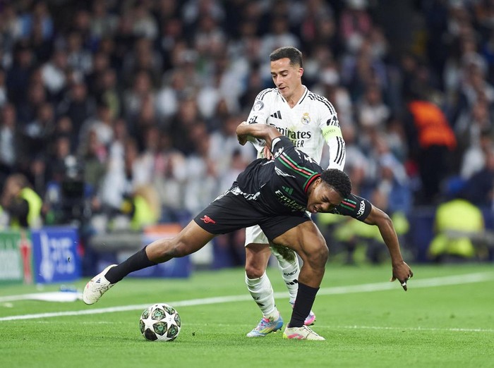 MADRID, SPAIN - APRIL 16: Lucas Vazquez (back) of Real Madrid competes for the ball with Myles Lewis-Skelly of Arsenal FC during the UEFA Champions League 2024/25 Quarter Final Second Leg match between Real Madrid C.F. and Arsenal FC at Estadio Santiago Bernabeu on April 16, 2025 in Madrid, Spain. (Photo by Mateo Villalba/Getty Images)