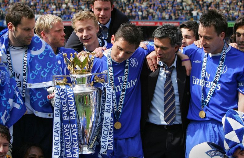 Chelsea players Petr Cech (L) John Terry (R) and Frank Lampard (C) look at the trophy with their Manager Jose Mourinho (2nd R) during the celebrations following the game against Charlton at Stamford Bridge in London 07 May 2005. Chelsea won the game 1-0 and were presented with the trophy and crowned Premiership champions. AFP PHOTO ADRIAN DENNIS No telcos, website uses subject to subscription of a license with FAPL on www.faplweb.com <https://www.faplweb.com> (Photo by ADRIAN DENNIS / AFP)