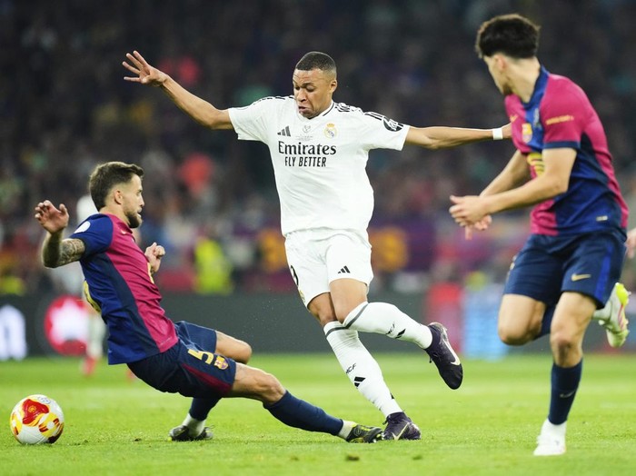 Real Madrid's Kylian Mbappe, centre, challenges for the ball with Barcelona's Inigo Martinez, left, during the Spanish Copa del Rey final soccer match between Barcelona and Real Madrid at Estadio de La Cartuja stadium in Seville, Spain, Saturday, April 26, 2025. (AP Photo/Jose Breton)
