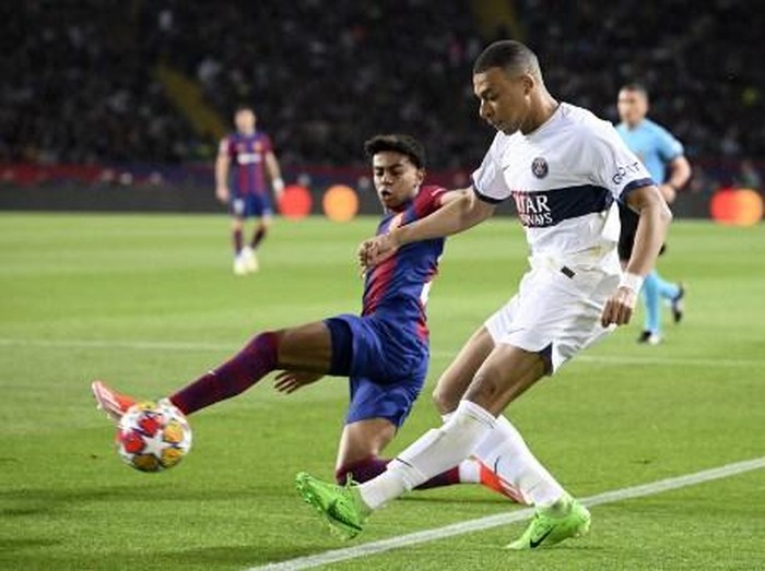 Barcelona's Spanish forward #27 Lamine Yamal (L) fights for the ball with Paris Saint-Germain's French forward #07 Kylian Mbappe during the UEFA Champions League quarter-final second leg football match between FC Barcelona and Paris SG at the Estadi Olimpic Lluis Companys in Barcelona on April 16, 2024. (Photo by Josep LAGO / AFP)