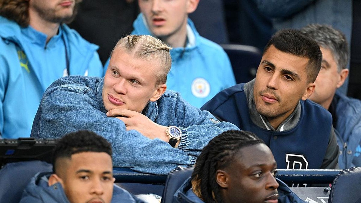 Erling Haaland (baris tengah sebelah kiri) duduk berdampingan dengan Rodri saat menonton laga Manchester City vs Aston Villa bulan lalu. Foto: Getty Images/Michael Regan