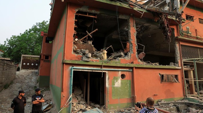 Police officers look on as a cameraman films the Bilal Mosque, after it was hit by an Indian strike in Muzaffarabad, the capital of Pakistan-administered Kashmir, May 7, 2025. REUTERS/Akhtar Soomro