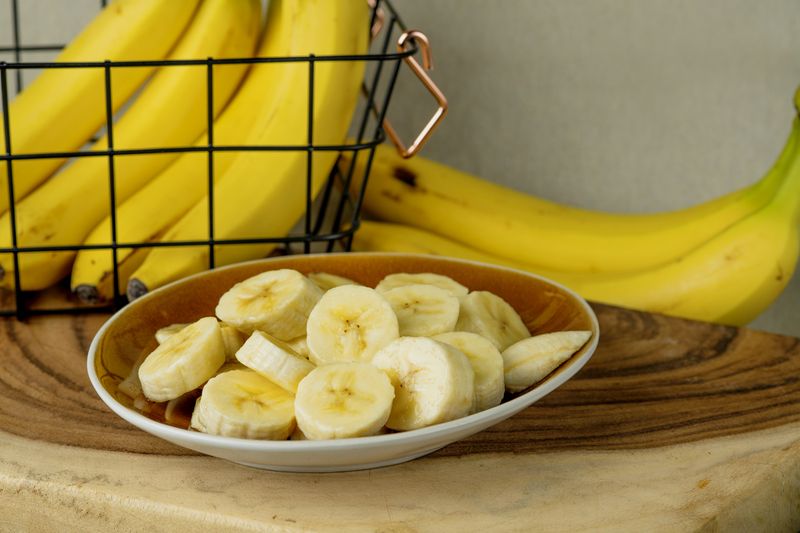 Fresh bananas and bananas cut into pieces in a bowl on the table - stock photo