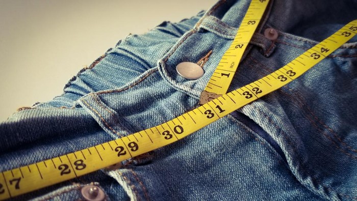 Yellow measure tape with blue jeans. women diet. Mock up for healthy lifestyle, body slimming, weight loss or dressmakers offer.